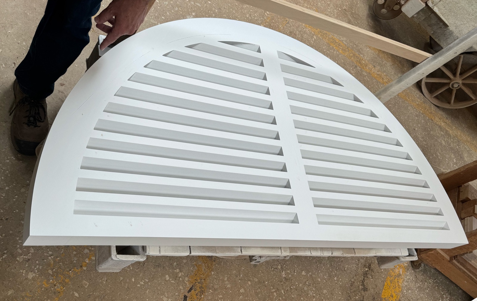 Arched louvered shutter panel finished and lying flat in the shop