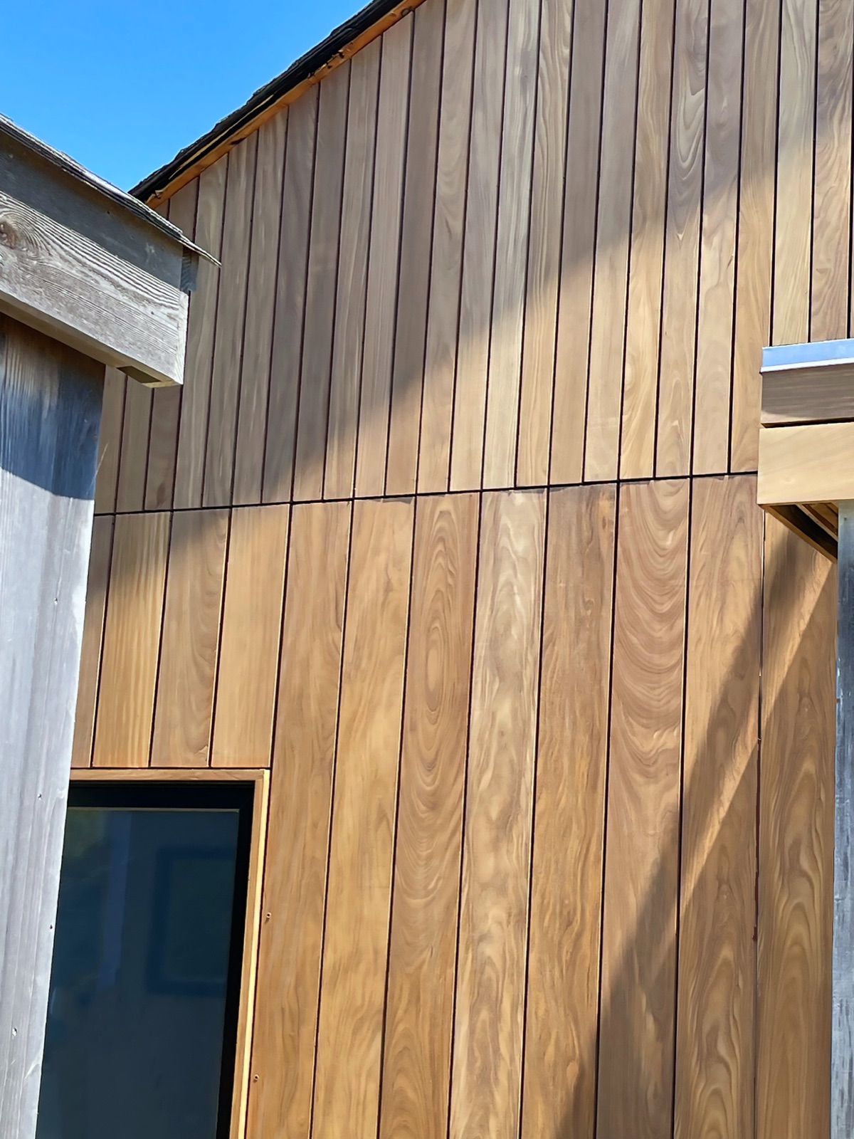 Vertical Afrormosia boards run across a building elevation