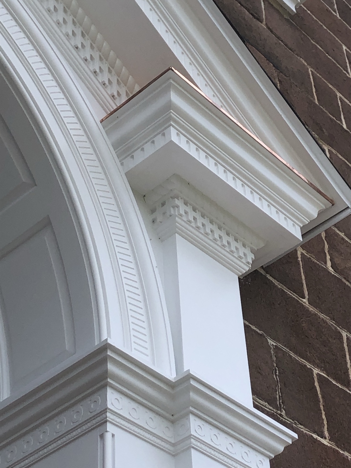 Painted millwork detail at the arch of a chapel facade